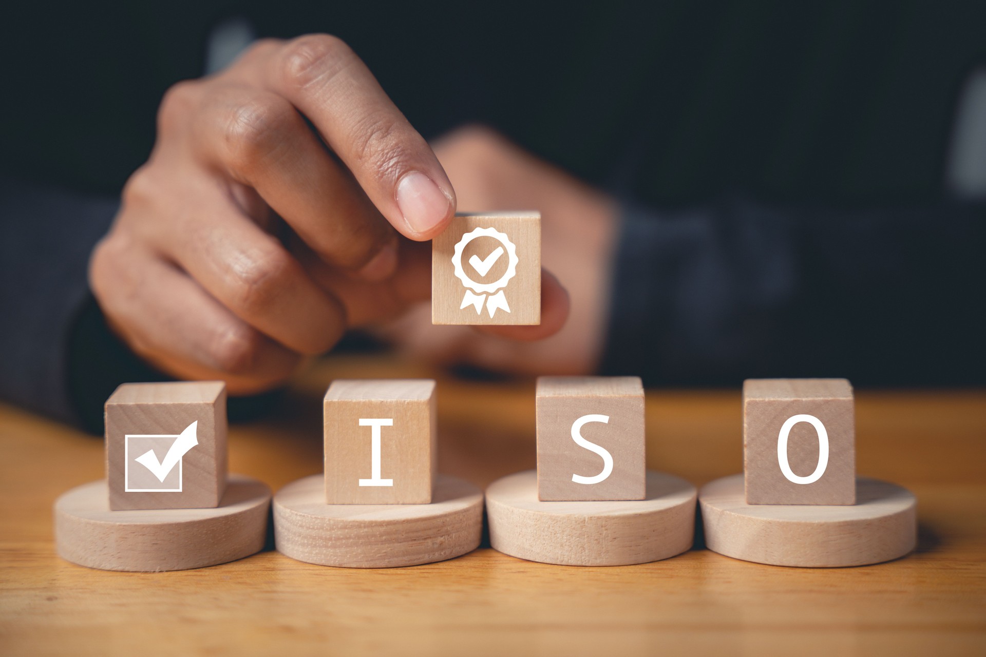 Businessman's finger pressing on ISO wooden cubes